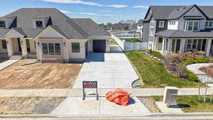 View of front facade with concrete driveway, an attached garage, a residential view, and a shingled roof