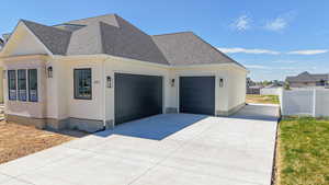View of property exterior with a shingled roof, concrete driveway, and an attached garage