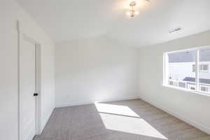 Unfurnished room with light carpet and vaulted ceiling