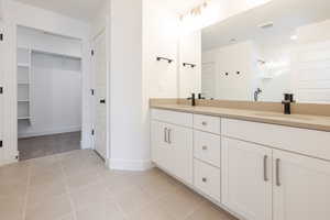 Bathroom featuring double vanity, a stall shower, a walk in closet, and light tile patterned floors