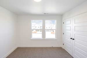 Unfurnished room featuring dark carpet and baseboards