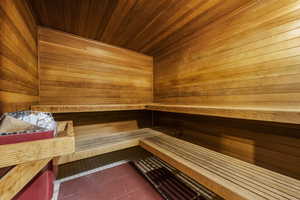 Relaxing sauna featuring wooden walls, wood ceiling, and tile patterned flooring