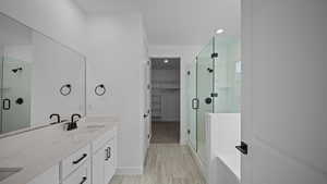 Bathroom featuring a shower stall, a spacious closet, double vanity, and recessed lighting