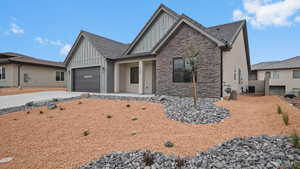View of front of home with board and batten siding, a garage, driveway, a porch, and stone siding