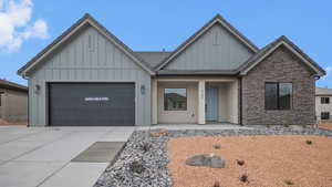 View of front of home with board and batten siding, stone siding, concrete driveway, a garage, and covered porch