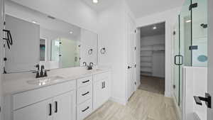 Bathroom with a spacious closet, a stall shower, double vanity, and recessed lighting