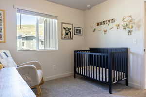 Carpeted bedroom with a crib and baseboards