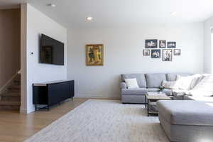 Living room featuring light wood finished floors, stairway, and recessed lighting