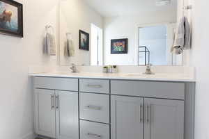 Full bath featuring double vanity and baseboards