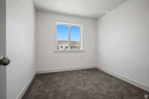 Unfurnished room with dark carpet and baseboards