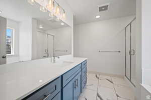 Full bathroom featuring light marble finish floors, vanity, and a stall shower