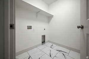 Washroom with hookup for an electric dryer, washer hookup, and marble look tile flooring