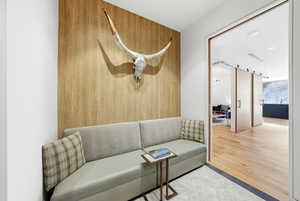 Living room with a barn door, light wood finished floors, and wood walls