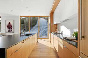 Kitchen featuring modern cabinets, dark countertops, light wood-style flooring, healthy amount of natural light, and recessed lighting
