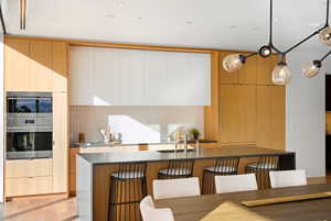 Kitchen with modern cabinets, hanging light fixtures, a breakfast bar area, and decorative backsplash
