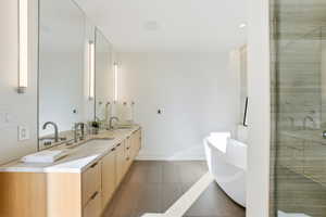 Bathroom featuring a freestanding bath, double vanity, a stall shower, and light tile patterned flooring