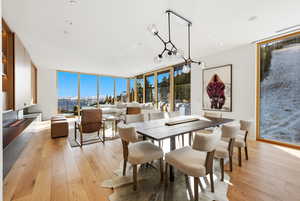 Dining room with floor to ceiling windows and light wood-type flooring