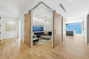 Corridor with a barn door, a chandelier, light wood-style floors, recessed lighting, and expansive windows