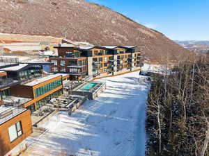 Snowy aerial view with a mountain view and a view of apartment building / complex