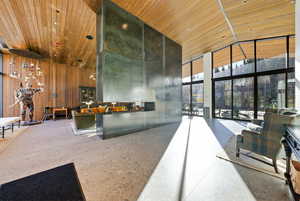 Lobby with high vaulted ceiling, wooden ceiling, expansive windows, and wood walls