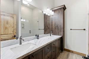 Bathroom with double vanity, a shower stall, and light wood-style floors