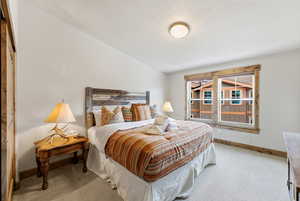 Bedroom featuring a textured ceiling, carpet floors, and vaulted ceiling