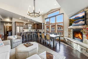 Living room with dark wood-type flooring, lofted ceiling, a chandelier, recessed lighting, and a fireplace