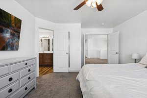 Bedroom with dark carpet, a ceiling fan, and ensuite bath