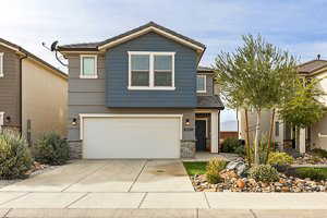 View of front of house with concrete driveway, an attached garage, and stone siding