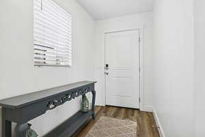Doorway to outside with wood finished floors and baseboards