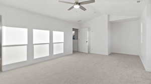 Empty room with light colored carpet, lofted ceiling, and ceiling fan