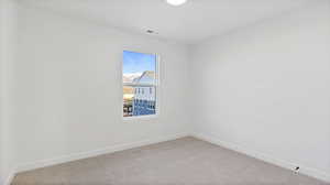 Carpeted spare room featuring baseboards