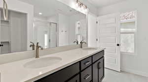 Bathroom with a shower stall, double vanity, and light tile patterned floors
