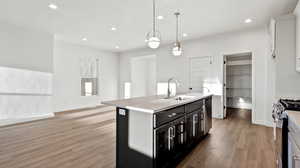 Kitchen featuring a kitchen island with sink, decorative light fixtures, light wood finished floors, recessed lighting, and open floor plan