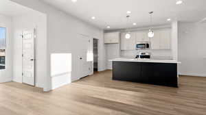 Kitchen with white cabinetry, decorative light fixtures, a kitchen island with sink, stainless steel appliances, and recessed lighting