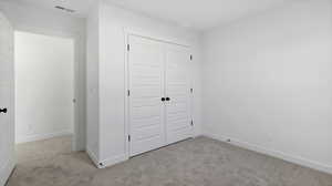 Unfurnished bedroom with light colored carpet and a closet