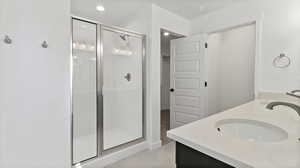 Full bath with double vanity, a stall shower, light tile patterned floors, and recessed lighting