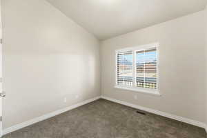 Empty room with carpet and lofted ceiling