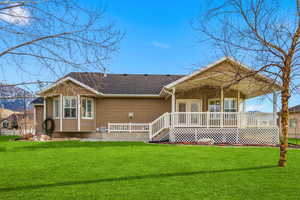 Rear view of property featuring a yard, a shingled roof, and a deck