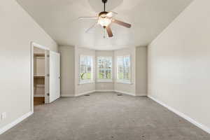 Unfurnished bedroom with a walk in closet, carpet floors, and ceiling fan