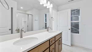 Bathroom with a shower stall, double vanity, and light tile patterned flooring