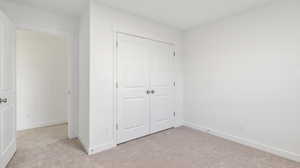 Unfurnished bedroom featuring light colored carpet and a closet