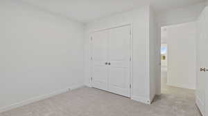Unfurnished bedroom with light colored carpet and a closet