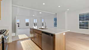 Kitchen with stainless steel appliances, open floor plan, light wood-type flooring, a kitchen island with sink, and recessed lighting