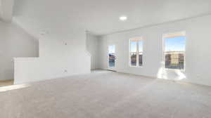 Unfurnished living room with light colored carpet and recessed lighting