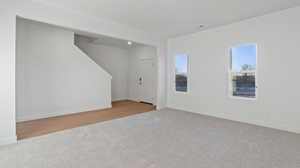 Unfurnished living room featuring light colored carpet and baseboards