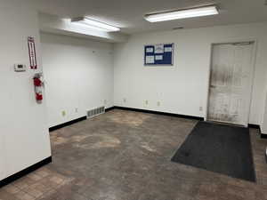 Empty room featuring brick patterned floors and a textured ceiling