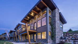 View of home's exterior featuring stone siding, a balcony, and a patio area