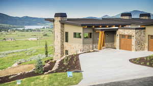 Contemporary home featuring a chimney, stone siding, a mountain view, and driveway