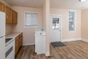 Kitchen featuring white appliances, brown cabinets, light countertops, and light wood finished floors